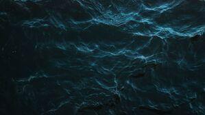 Mysterious dark ocean surface with subtle light reflections and deep blue hues